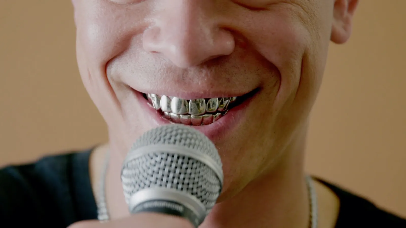 Artist with silver grills singing into a microphone